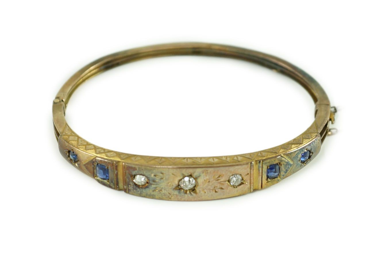 A late Victorian engraved gold, gypsy set three stone diamond and four stone sapphire set hinged bangle